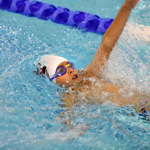 Young swimmer doing backstroke