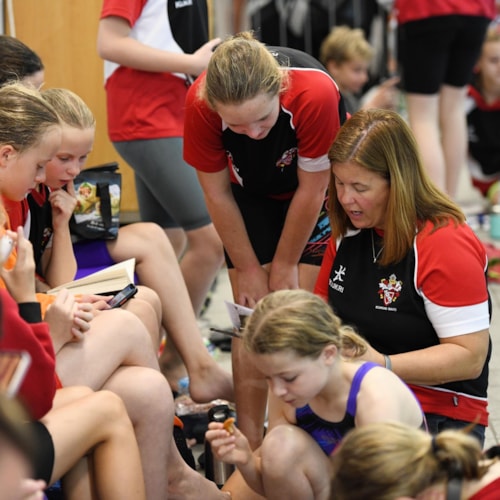 Coach talking to group of young swimmers